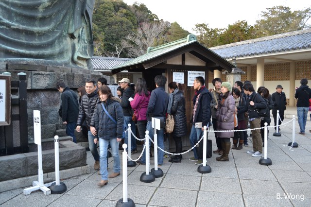 A long line of people queue up to go inside the Buddha. 